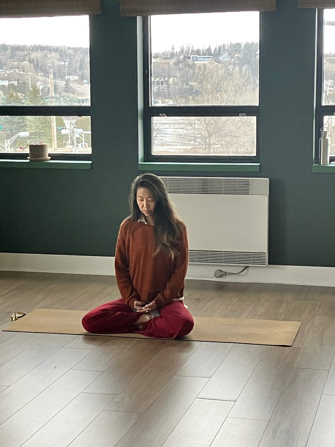 Letitia Rose assise en méditation dans une salle de pratique avec lumière naturelle.