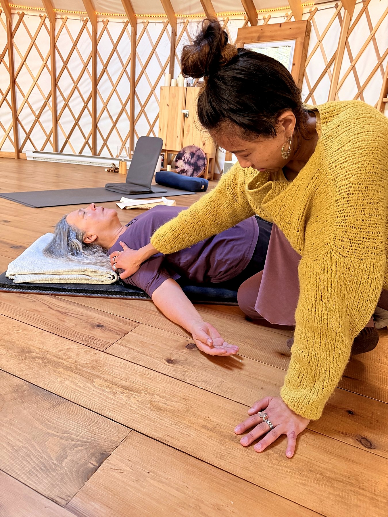 Letitia Rose soutient une personne allongée pendant une pratique douce sur tapis.