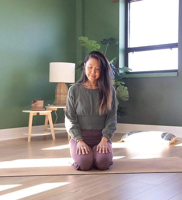 Letitia Rose agenouillée sur un tapis de yoga dans un espace de pratique lumineux